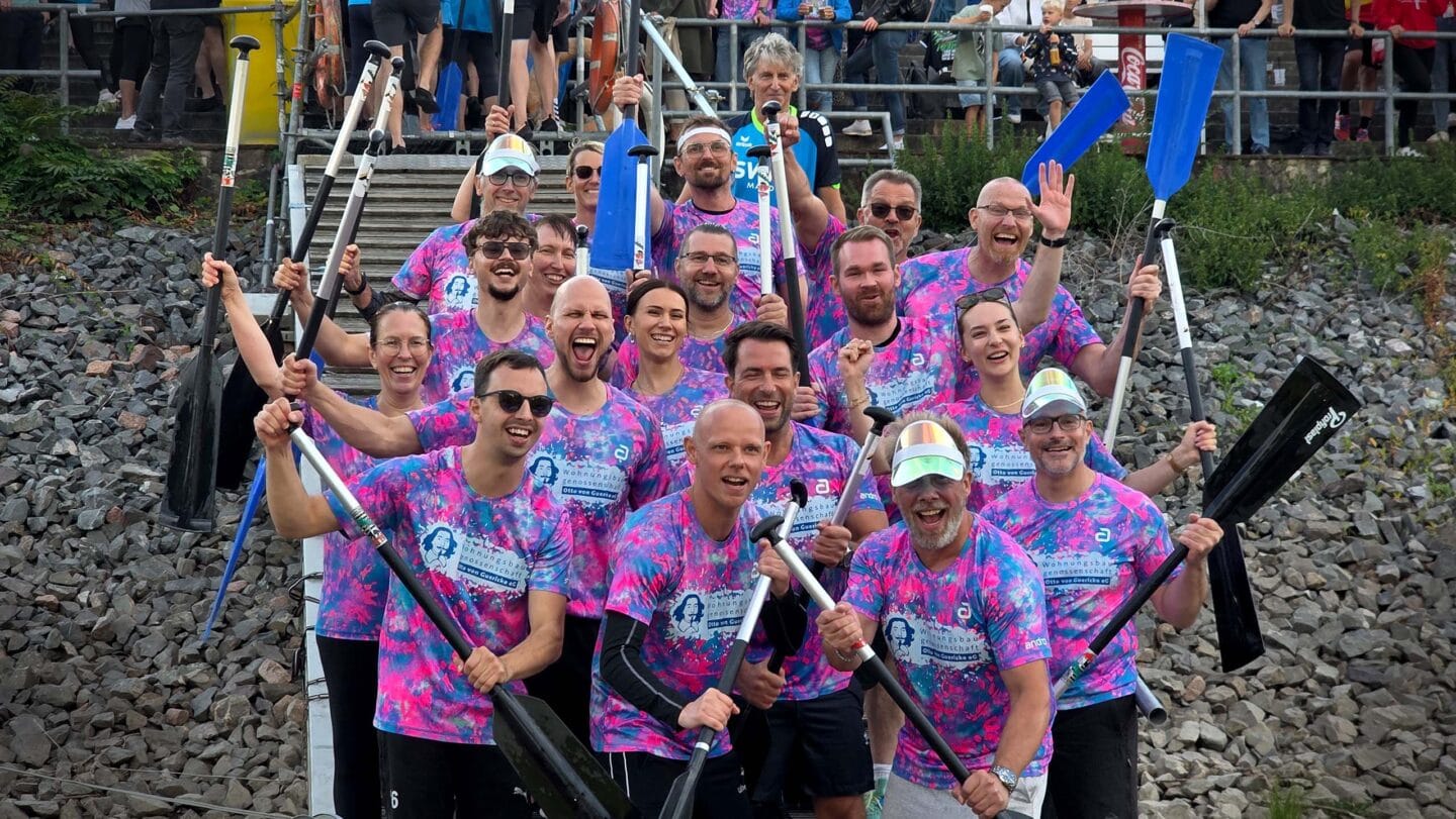 Eine Gruppe von Menschen sthene in bunten T-Shirts und Paddeln in der hand und jubeln.