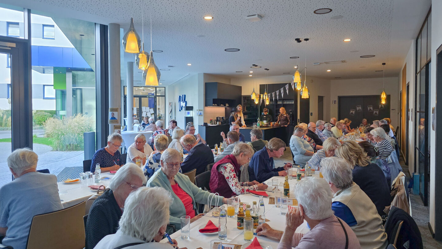 Eine Gruppe Menschen sitzen am Tisch und unterhalten sich und schreiben auf Zetteln.